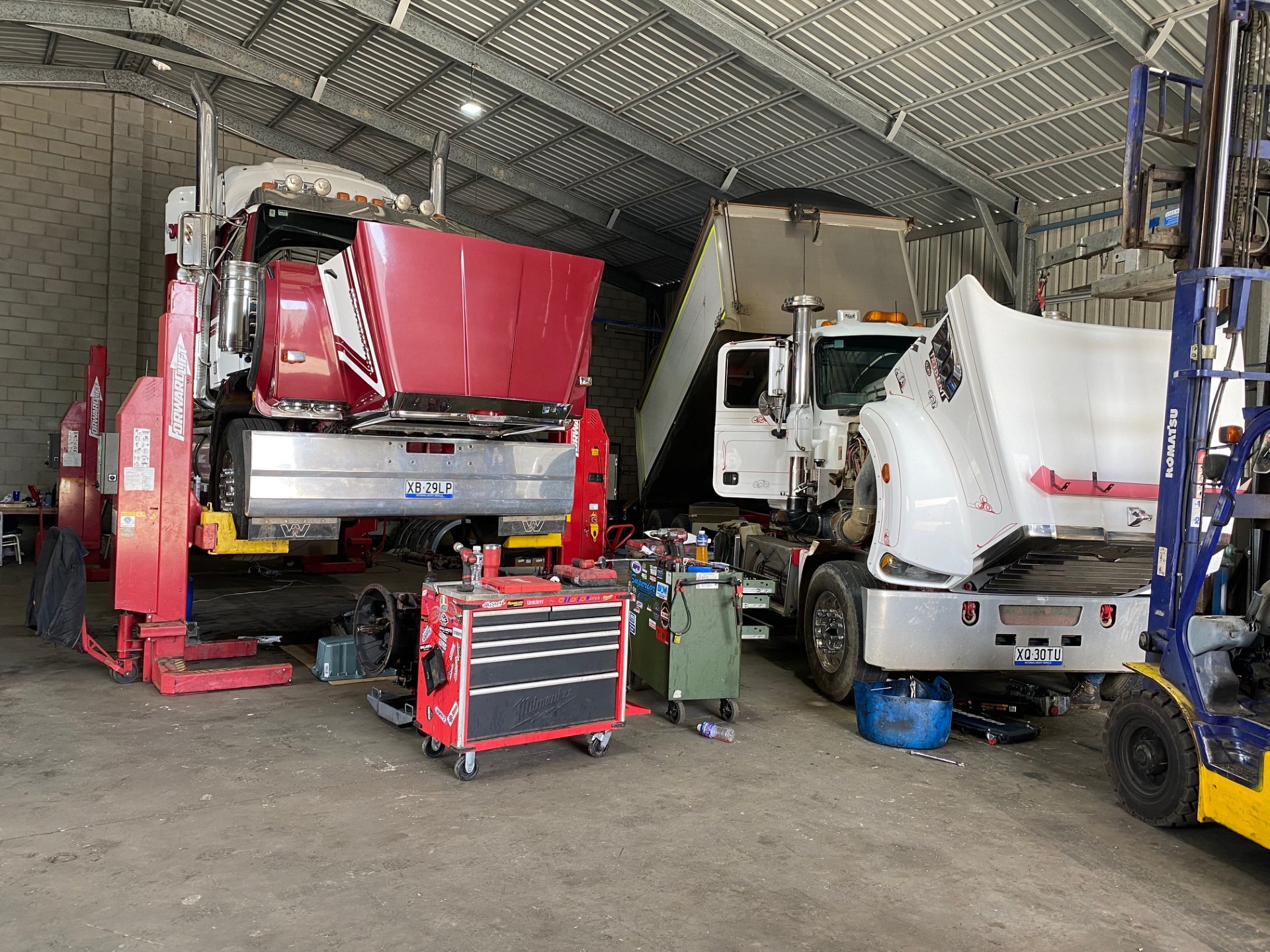 Prime movers raised on hoists in the Direct Diesel Repairs workshop bays during wheel bearing and brake work