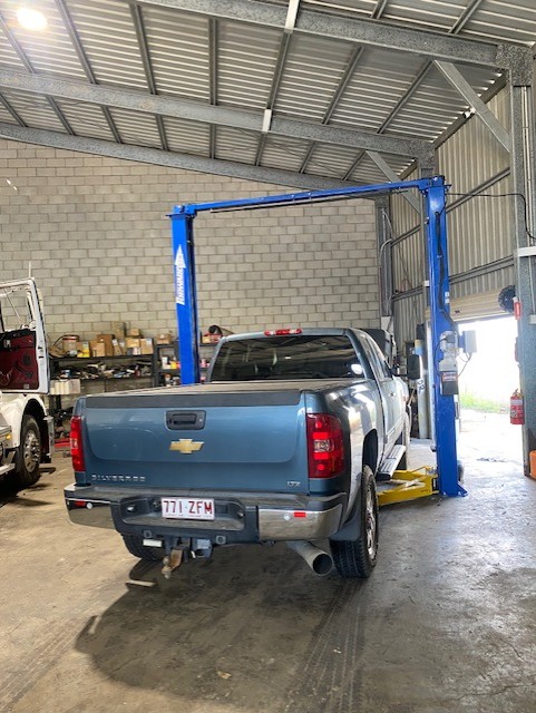 Chevrolet Silverado raised on a two-post hoist in the workshop for heavy vehicle servicing