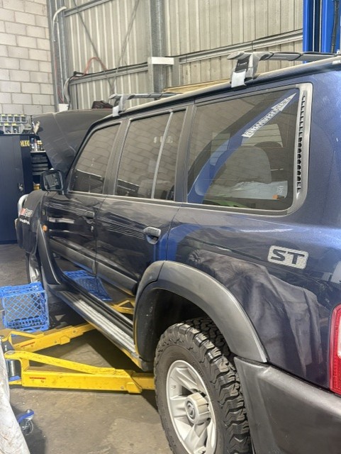 Nissan Patrol 4x4 raised on the workshop hoist during a log book service