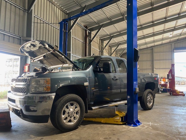 Chevrolet Silverado on a workshop hoist with the bonnet open during a maintenance inspection