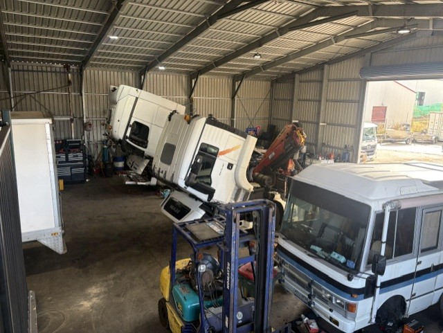 Truck cab tilted forward and fleet vehicles inside the Direct Diesel Repairs workshop bay